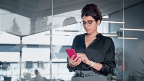 Young Indian or arabian business woman ceo manager using cell phone mobile application. Smiling Latin Hispanic businesswoman holding smartphone for finance work chat online in office. Copy space - Powered by Shutterstock - Get 15% off with code: PIKWIZARD15