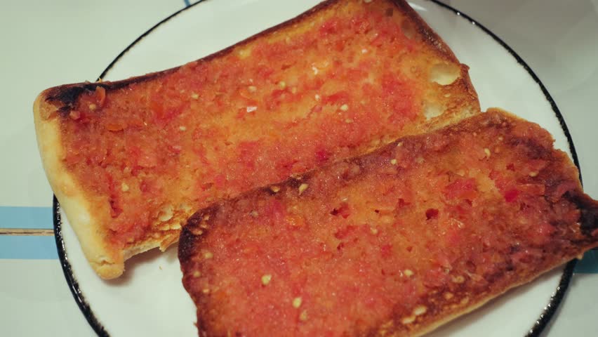 Pan con tomate a traditional dish of Catalan cuisine. Lightly toasted slice of white bread rubbed with garlic and tomato with the addition of olive oil and salt. High quality 4k footage