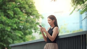 Thoughtful asian woman standing in park using smartphone while smiling gently, enjoying peaceful moment texting or browsing social media outdoors with digital lifestyle in green city environment - Powered by Shutterstock - Get 15% off with code: PIKWIZARD15