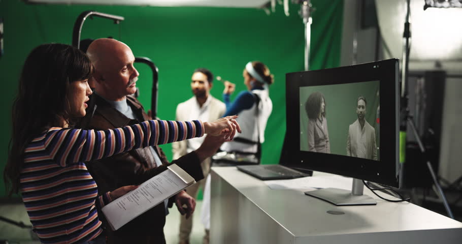 Director, green screen and assistant with videographer in production studio for filmmaking or cut. Man, woman or producer checking footage with help for commercial, playback or recording on set