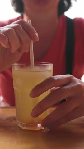 Vertical close-up of woman with citrus juice and straw at cafe