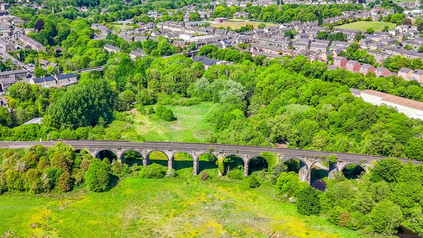 A rotating aerial view of the viaduct over the River Sett and the town of New Mills, Derbyshire, UK in summertime