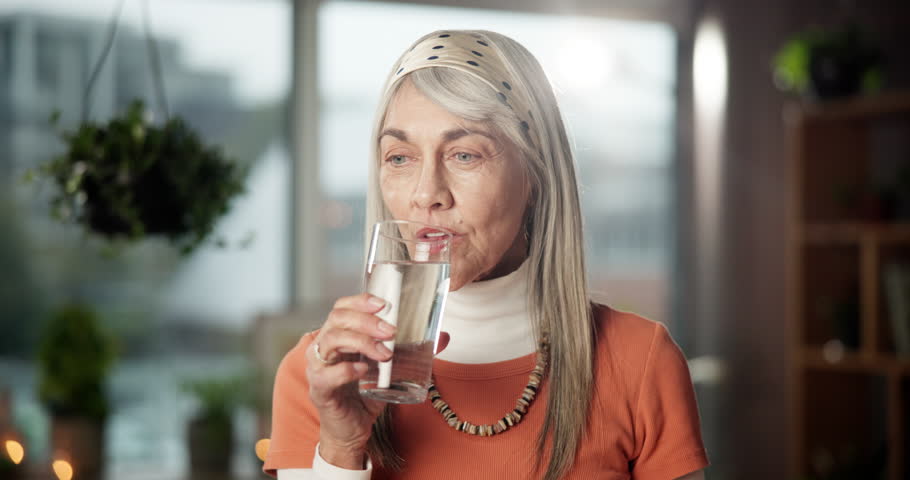 Drinking water, smile and thinking with mature woman in home for health, vision or wellness. Beverage, hydration and reflection with happy senior person in apartment for memories or nostalgia