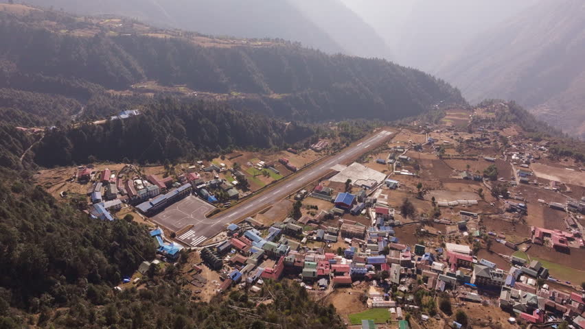 Aerial view of Lukla Airport and its dangerous runway, nestled in the Himalayas, showing surrounding villages and mountainous landscape