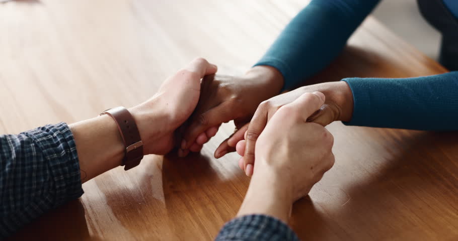 Therapy, support and couple holding hands on table for love, apology and trust in home. Forgive, kindness and people bonding together for empathy, partner and commitment for relationship and care