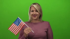 Young blonde woman points finger to us flag in green studio setting while smiling cheerfully; pride. - Powered by Shutterstock - Get 15% off with code: PIKWIZARD15