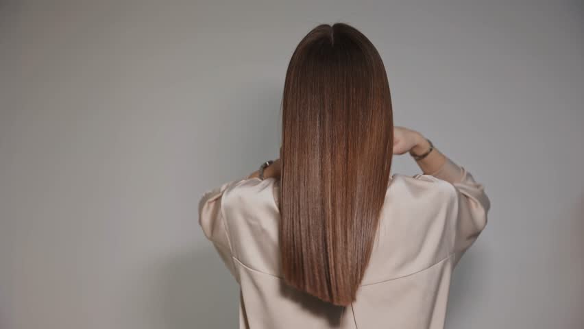 Woman shows healthy strong and shiny hair after keratin haircare treatment procedure in salon hairdresser.