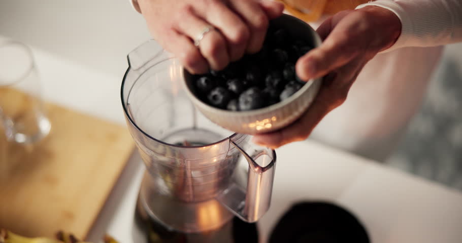 Blueberries, blender and woman with smoothie in kitchen for liquid breakfast with diet, health or wellness. Nutrition, fruit and hands of person with beverage for morning meal in home from above.