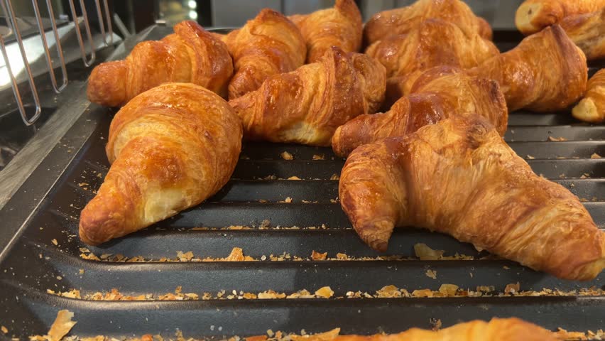 Tracking shot on freshly baked croissants displayed in self-service shelf in supermarket