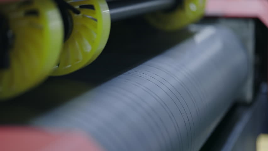 Close-up of industrial printing machine rolling colored sheets at high speed. Precision printing for packaging materials in modern manufacturing.