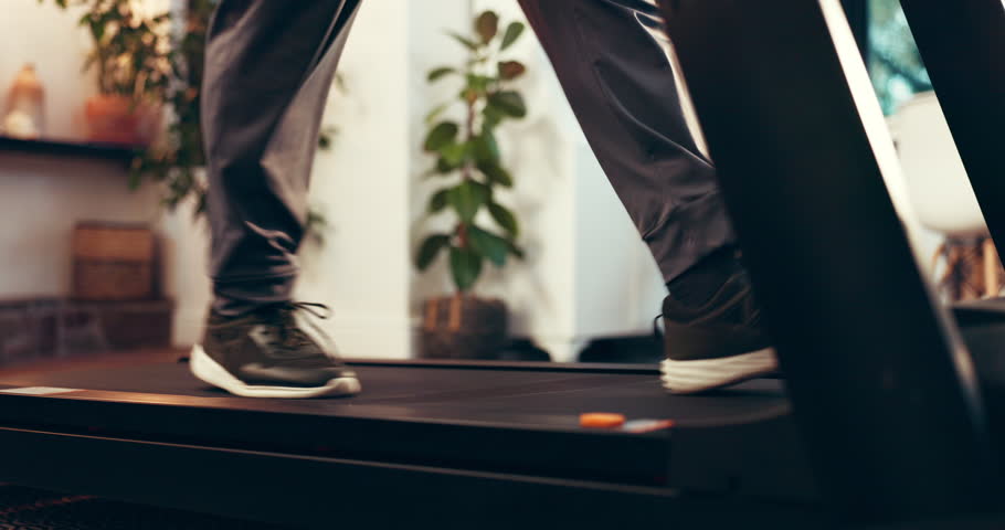 Feet, treadmill and walking with person in home for activity, exercise or fitness routine. Physiotherapy, rehabilitation and wellness with legs in apartment with machine, cardio training or health