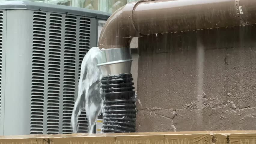 Water pours out of a residential downspout connection during heavy rain. The drainage pipe overflows under intense downpour, illustrating poor runoff control near the house foundation. 14713  	