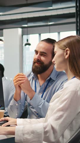 Vertical video Friendly team leader helping happy young engineer code AI algorithms to debug software issues and improving system stability. Helpful manager assisting smiling intern in tech startup