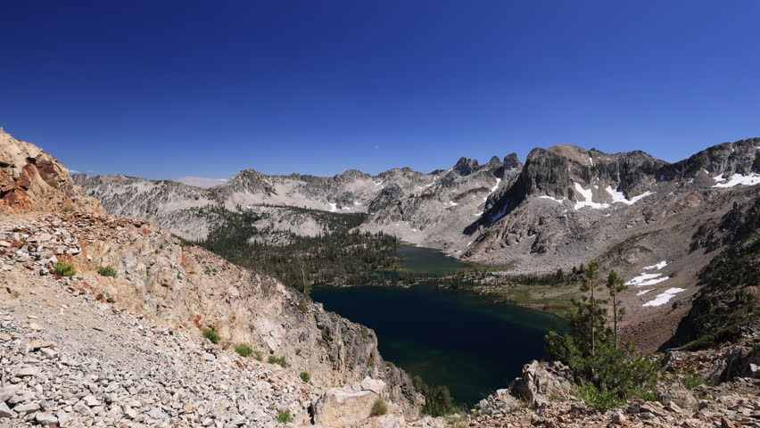 Twin Lakes shimmer in the valley below Snowyside Pass in Idaho’s rugged Sawtooth Mountains, reflecting the clear blue sky on a perfect summer day.