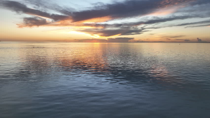 A colorful sunset reflects off the calm seas in a remote part of the tropical Pacific Ocean.
