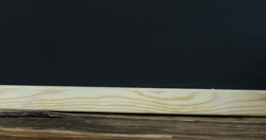 Different books, pencils and red apple on wooden table near blackboard, closeup. Camera moving right