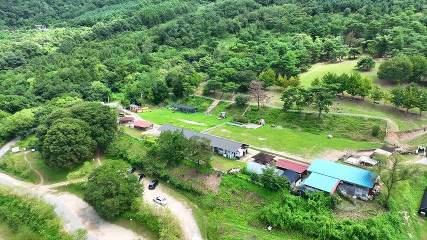 Aerial view of a traditional rural farm and green pasture surrounded by forest in Chuncheon, South Korea