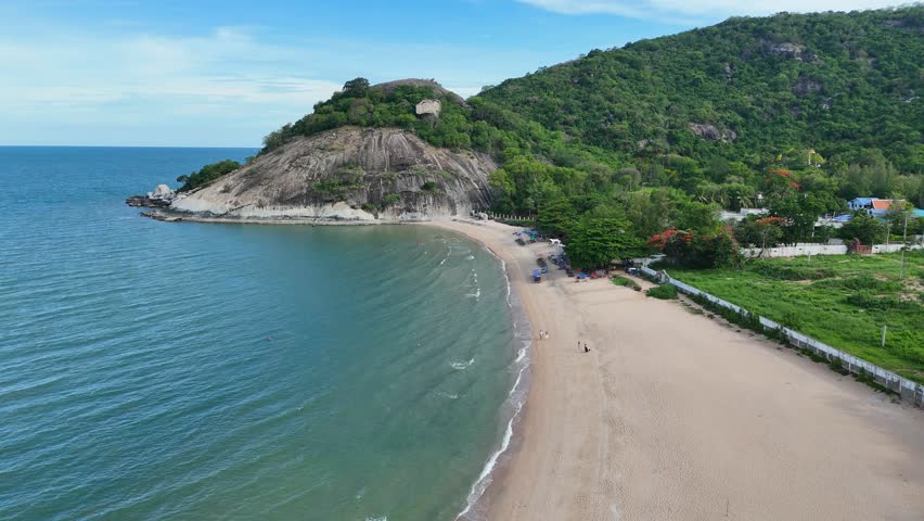 Peaceful Thai beach below tropical green mountain slope