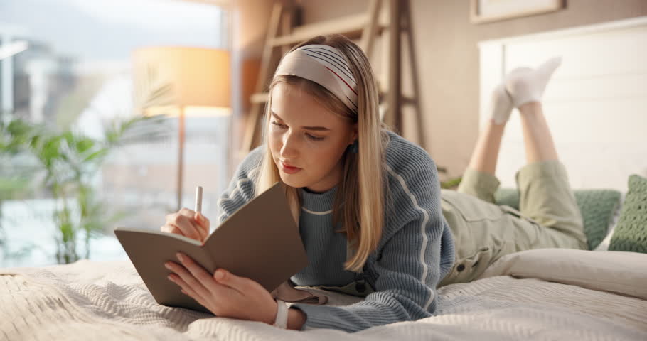 Woman, writing and lying with book in bed for story, schedule reminder or diary in home. Female person, freelancer or journalist taking notes in bedroom for new novel, ideas or inspiration in house