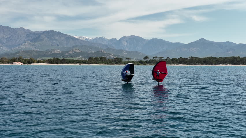Two Wingfoil Racers Gliding Along Scenic Coastline