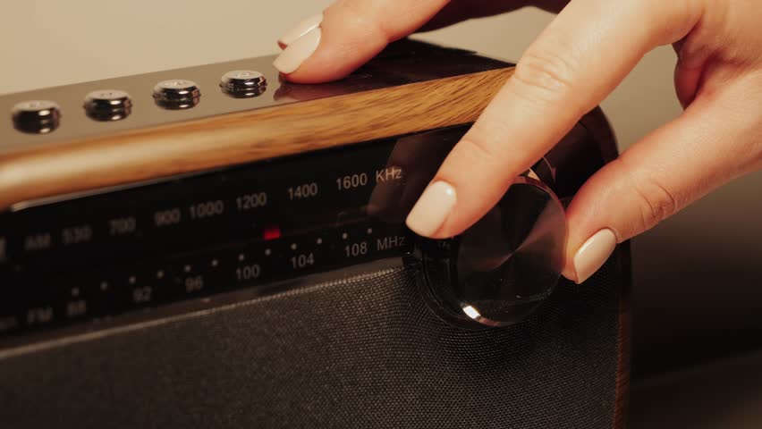 Close-up of a radio dial. A hand turns the tuning knob. Tuning a radio station frequency. High quality 4k footage