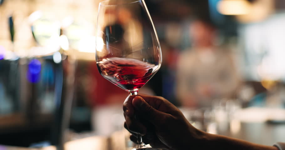 Drinking, wine and man in pub, enjoy and glass with alcohol on weekend, night or swirling for taste. Relax, customer and person with beverage for break, evening and leisure with liquor in bar