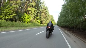 Motorcyclist races motorcycle on woodland country road. Man in helmet rides on sport motorbike at rural road near forest. Guy driving bike during trip. Concept of freedom and adventure. Aerial shot - Powered by Shutterstock - Get 15% off with code: PIKWIZARD15