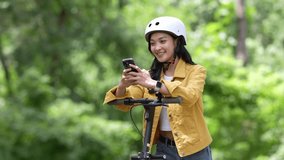 Young woman enjoying e scooter ride through park, navigating with smartphone while wearing safety helmet, embodying urban mobility lifestyle - Powered by Shutterstock - Get 15% off with code: PIKWIZARD15