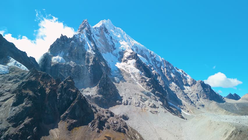 Snow covered mountain peaks shine in bright light over dry terrain on Salkantay Trek in Peru, establishing rugged aerial