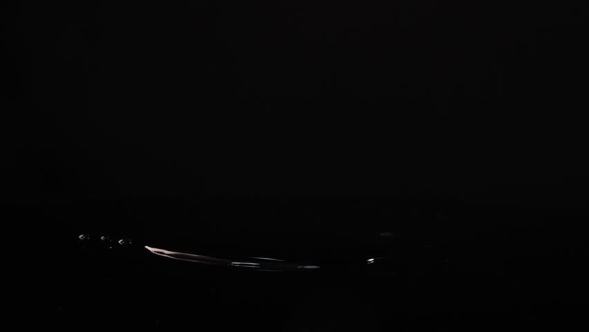 Lime slices fall and splash on a reflective black surface, captured in slow motion with dramatic lighting