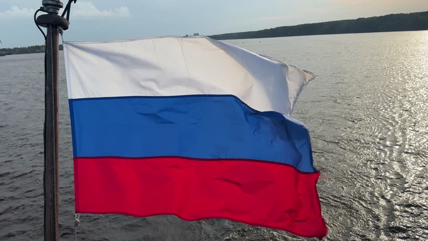 Russian tricolor flag proudly waves at the stern of the ship, fluttering in the wind during voyage.
