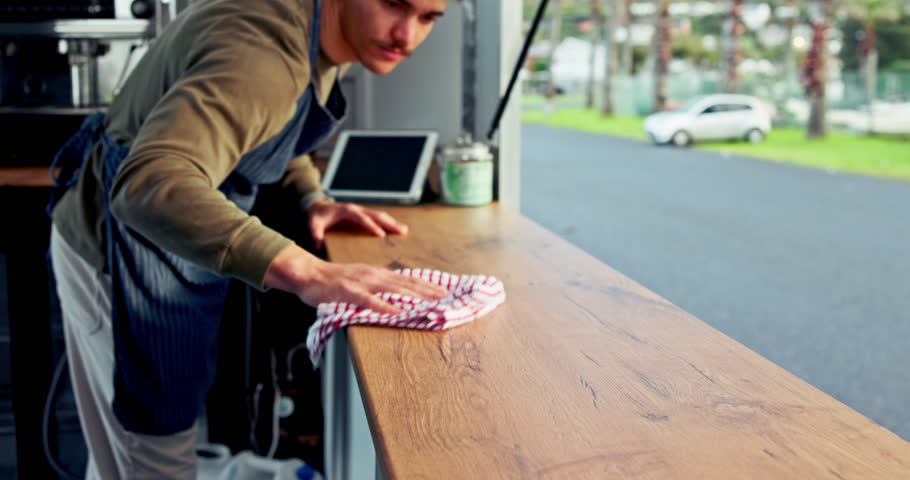 Food truck, wipe and man cleaning outdoor for service at small business, restaurant and mobile cafe. Server, owner and person with cloth for maintenance, disinfection and sanitation for hygiene