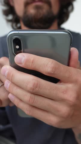 Scrolling smartphone screen on vertical hands close-up. Close-up vertical shot of fingers scrolling on mobile phone touchscreen. Communication, chat, scrolling in portrait 9:16 video format.