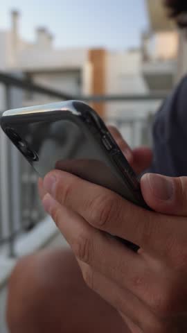 Scrolling social media feed on vertical hands close-up. Close-up vertical shot of fingers scrolling on mobile phone touchscreen. Communication, chat, scrolling in portrait 9:16 video format.