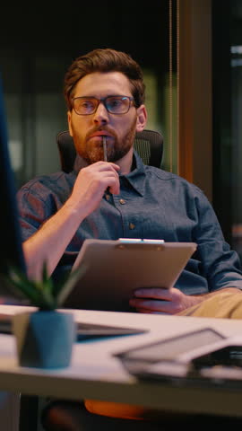 Caucasian business man trader businessman analyst writing document in night office paperwork overtime evening working online trading thinking write notes thoughtful guy male developer think ideas task