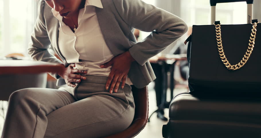 Stomach, pain and hands of woman in lobby with period ache in abdomen, ibs or travel medical emergency. Health, business person and work trip with constipation, digestion or menstrual cramps