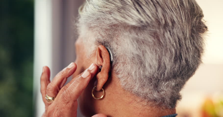 Hands, senior woman and hearing aid in home with implant, test and fitting for comfort in retirement. Back, listen and medical audio tech for elderly person with disability, deaf and click at house