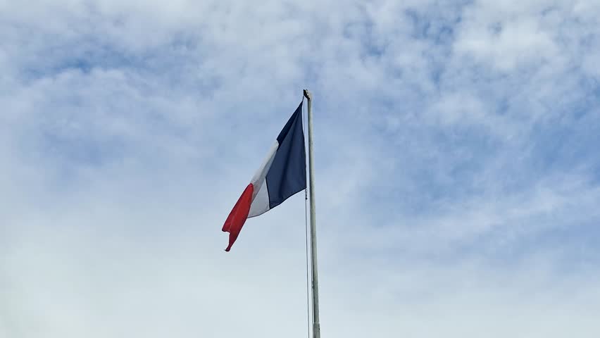 The French Flag on blue cloudy sky.