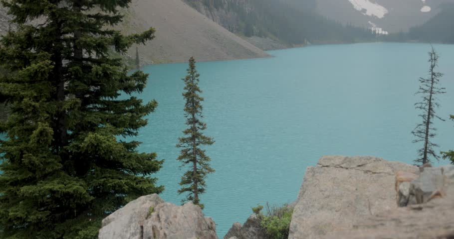 Beautiful blue waters of Moraine Lake and the mountains surrounding the lake in Banff National Park Alberta on a slightly foggy afternoon.