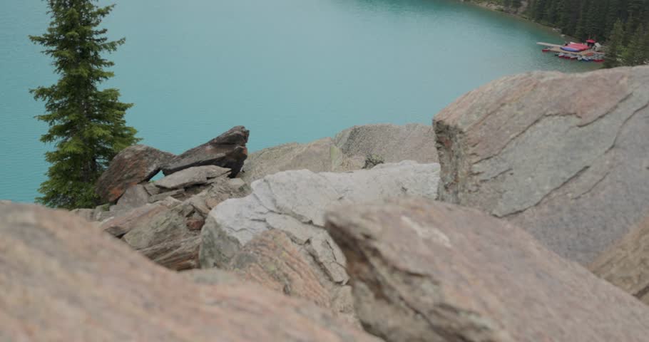 Panning up to see the crystal clear blue waters of Moraine Lake in Banff National Park Alberta and the mountains in the background.