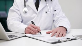Close up. Male doctor signing medical documents in hospital office. Physician in lab coat reviewing a report on clipboard, writing prescription and filling out patient records or treatment conclusion - Powered by Shutterstock - Get 15% off with code: PIKWIZARD15