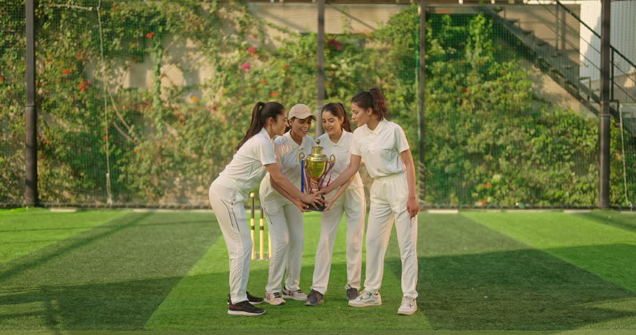 Indian young adult gen z sports woman group team standing win cricket match trophy do celebrate outdoor playground. Happy playful female player cheering jumping clap hand hugging outside play ground