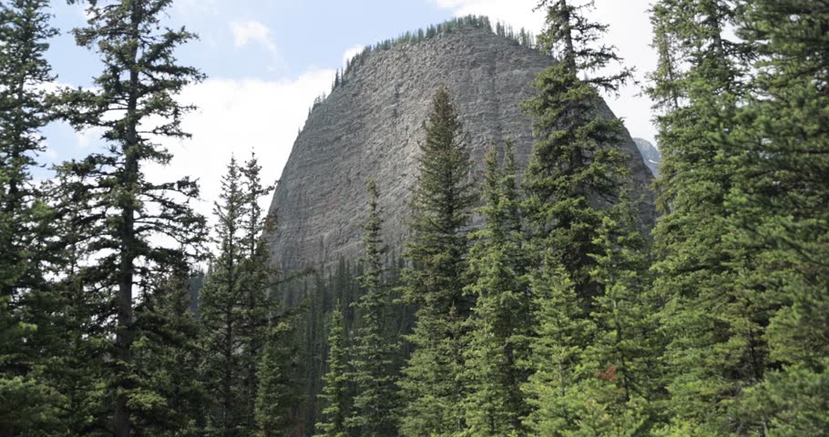 Beautiful view of a rocky mountain top with trees around it from the hiking trail up to Lake Agnes Tea House on Mount St. Piran and Mount Whyte, within Banff National Park near Lake Louise Alberta.