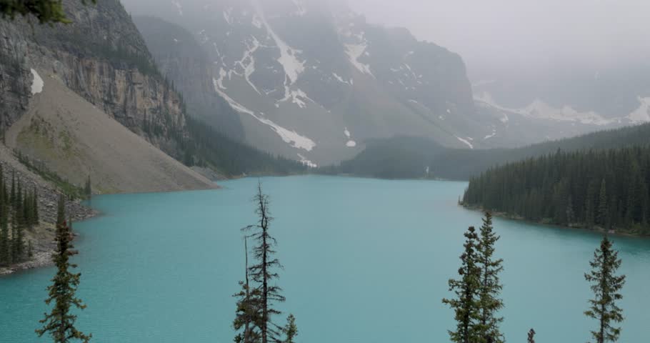 Crystal clear blue Moraine Lake in Banff National Park Alberta on a slightly foggy afternoon.