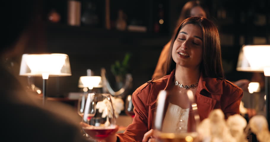 Date, romance and toast with couple in restaurant at night for anniversary, bonding or celebration. Cheers, fine dining and wine with happy people drinking alcohol at table for evening conversation