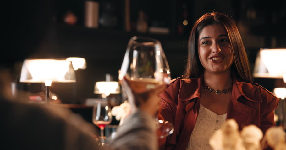 Date, romance and toast with couple in restaurant at night for anniversary, bonding or celebration. Cheers, fine dining and wine with happy people drinking alcohol at table for evening conversation