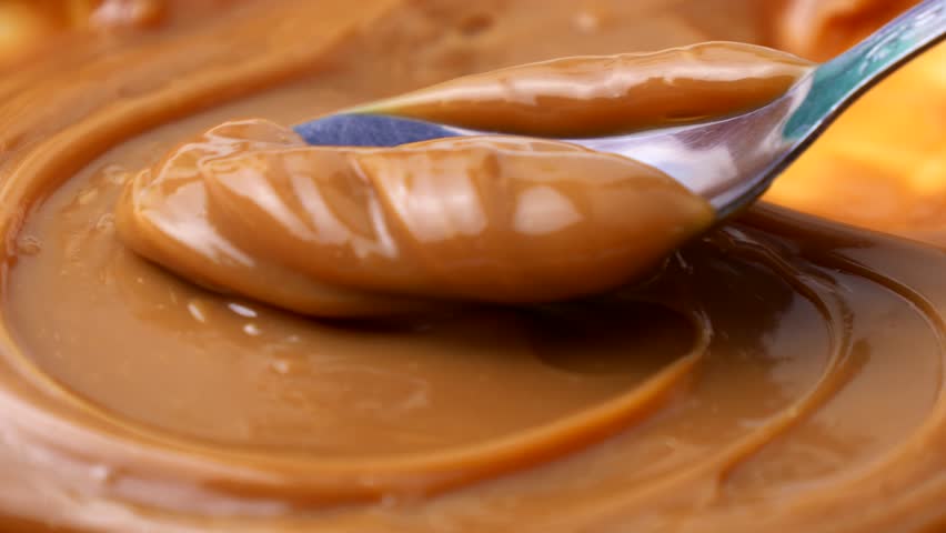 Sweet brown caramel toffee sauce spreading with a spoon close up
