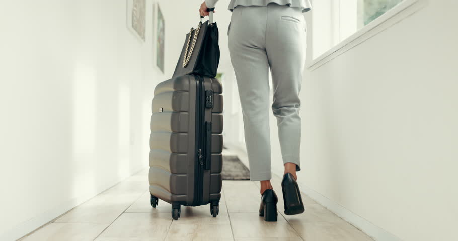 Business, legs or walking with suitcase to hotel room for accommodation, guest arrival or check in. Corporate trip, back or woman with luggage in lodge corridor for booking reservation or hospitality