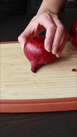 woman hands peeling red onion on wooden board close up vertical video