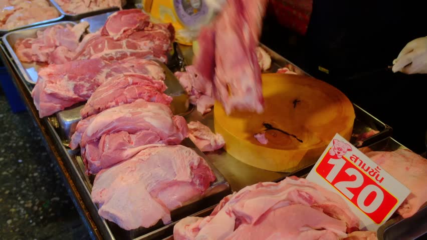Vendor stall cutting selling fresh meat for retail sales to customers, Thailand.Thai language on the pork belly sign